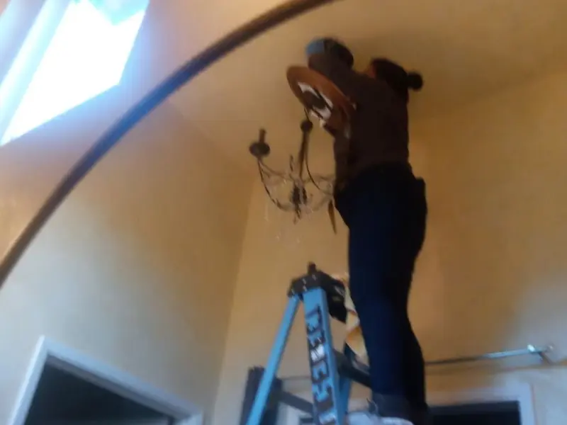 Electrician installing a chandelier in a West Memphis residence